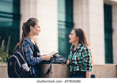 Girls Seriously Discussing About Their Studies On The First Day Of School. Standing Outside School In Trendy Outfit. Happiness Of Seeing Best Friend Is On Their Faces. Student Girls Back To School