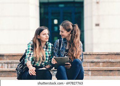 Girls Seriously Discussing About Their Studies On The First Day Of School. Standing Outside School In Trendy Outfit. Happiness Of Seeing Best Friend Is On Their Faces. Student Girls Back To School