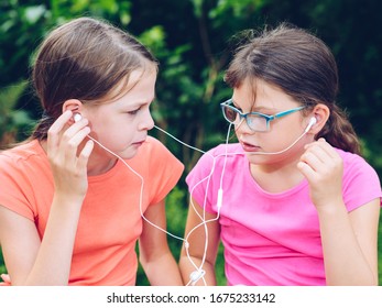 Girls Sharing Headphones To Listen To Music. Happy Friends Spending Time Together.