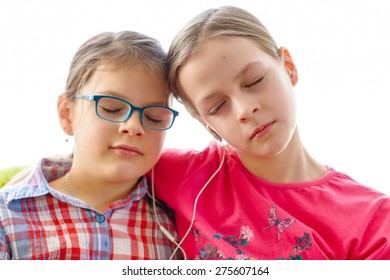 Girls Sharing Headphones To Listen To Music - Eyes Closed. Happy Friends Spending Time Together.