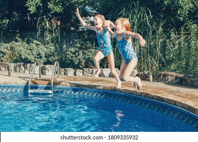 Girls Sisters Diving In Water On Home Backyard Pool. Children Siblings Friends Enjoying And Having Fun In Swimming Pool Together. Summer Outdoor Water Activity For Kids. 