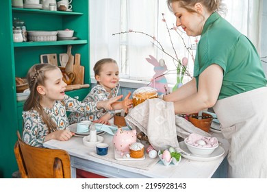 Girls, Sisters, Mother At Table With Easter Decoration. Celebration In Kitchen.Tablescape For Home Easter Holiday.Family Religious Traditional Festive Food, Meal. Colored Eggs,cake, Fun, Bunny Ears.