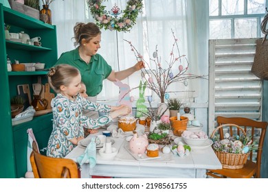 Girls, Sisters, Mother At Table With Easter Decoration. Celebration In Kitchen.Tablescape For Home Easter Holiday.Family Religious Traditional Festive Food, Meal. Colored Eggs,cake, Fun, Bunny Ears.