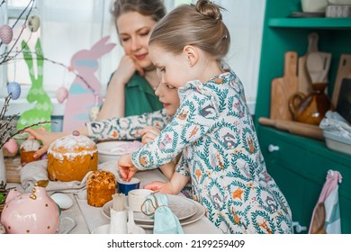 Girls, Sisters, Mother At Table With Easter Decoration. Celebration In Kitchen.Tablescape For Home Easter Holiday.Family Religious Traditional Festive Food, Meal. Colored Eggs,cake, Fun, Bunny Ears.