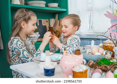 Girls, Sisters At Table With Easter Decoration. Celebration In Kitchen.Tablescape For Home Easter Holiday.Family Religious Traditional Festive Food, Meal. Colored Eggs,cake, Funny Bunny, Candy Sweet.