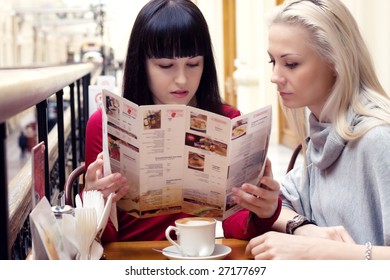 Two?pretty Girls Sitting By The Table In Cafe And Reading Menus