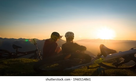 Girls sitting on mountain with bycicles looking at sunset and talking. Enjoying in beautiful nature. - Powered by Shutterstock