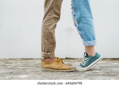 Mädchen steht auf Zehenspitzen und küsst ihren Mann - Nahaufnahme von Schuhen