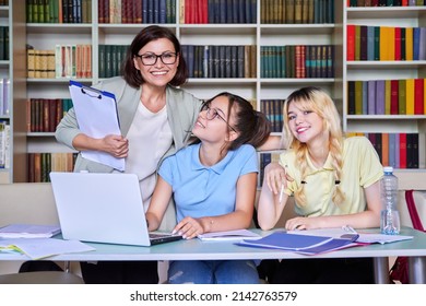 Girls Teenage Students Studying In Library With Teacher Mentor