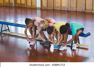 Girls tying shoe laces in basketball court at school gym - Powered by Shutterstock