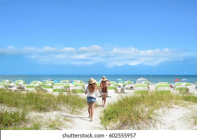 Girls Walking On The Beach On Summer Vacation.  Beach Chairs And Parasols On Beautiful White Sand In The Background.  Gulf Of Mexico, Clearwater Beach, Florida, USA.