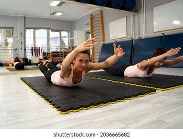 Girls In Women Gym Holding Arms And Legs Up, While Laying On Stomach, Core And Back Exercise