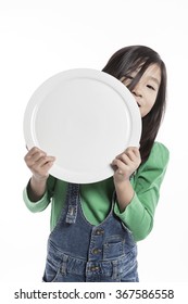 A Girls(woman, Female) Wearing Green Shirts And Blue Pants Hold A Blank, Empty Ceramic Food Tray(dish) With Smile(happy) Isolated White At The Studio.