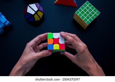 Girona, Spain; 11 09 2020: Woman Solving A Puzzle Cube With A Lot Of Different Cubes Around