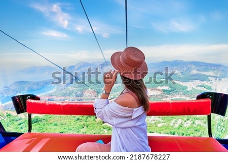 Girt tourist traveler sitting in cable car cabin during trip to viewpoints in the mountains