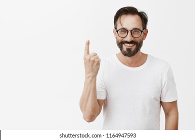 Give Me One Minute To Dress Up. Charming Carefree Friendly-looking Bearded Man In Trendy Glasses, Showing Index Finger, Numering Reasons Why He Loves Wife, Smiling Broadly With Caring Expression