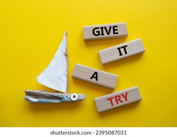 Give it a try symbol. Concept words Give it a try on wooden blocks. Beautiful yellow background with boat. Business and Give it a try concept. Copy space. - Shutterstock ID 2395087031