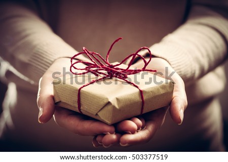Giving a gift, handmade present wrapped in paper. Christmas time, vintage mood.
