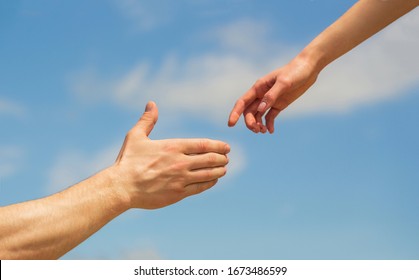 Giving a helping hand. Hands of man and woman on blue sky background. Lending a helping hand. Solidarity, compassion, and charity, rescue. Hands of man and woman reaching to each other, support. - Powered by Shutterstock
