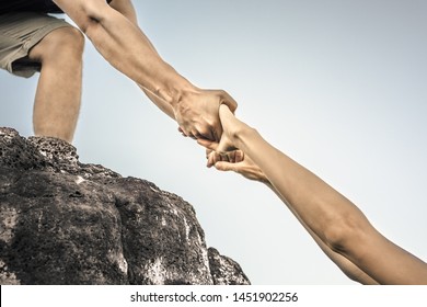 Giving a helping hand up a mountain. Helping someone in need concept. 