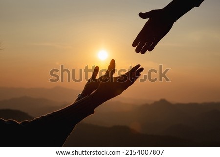Giving a helping hand on the background of the dawn 