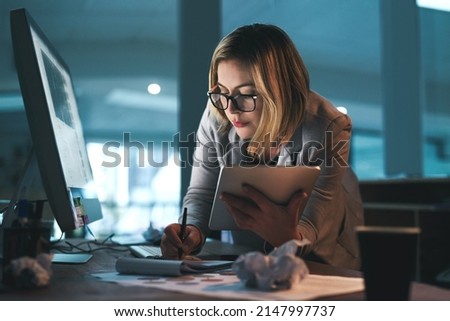Giving it her all, throughout all hours. Shot of a young businesswoman working late on a digital tablet in an office.