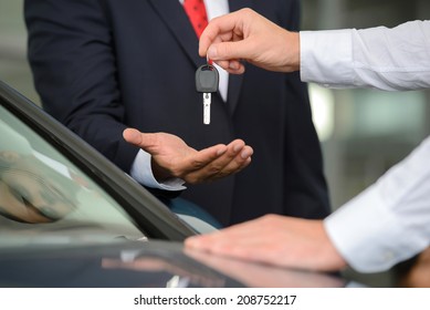 Giving A Key Of A Brand New Car. Handsome Young Classic Car Salesman Giving A Car Key To The Owner And Smiling