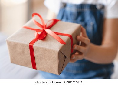 Giving receiving presents concept. Small kid child receiving giving gift box present with red ribbon on Christmas birthday holiday event celebration, closeup cropped shot - Powered by Shutterstock