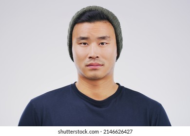 Giving You Nothing But A Blank Stare. Studio Portrait Of A Handsome Young Man Posing Expressionless Against A Grey Background.