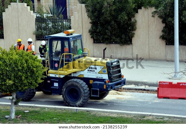 Giza, Egypt, March 14 2022: selective focus of\
heavy yellow bulldozer, grader and excavator construction\
equipment, end loader vehicle, bulldozer quarry machine, stone\
wheel yellow digger with\
workers