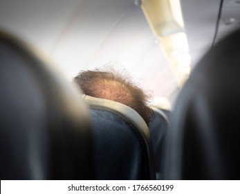 Glabrous Man Head On Aircraft Seat. Hidden Camera View From Back Seat. Bald Head Thin And Scalp And Broken Hair. Concept Healthcare.  