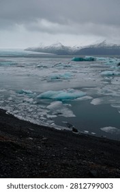 Glacial ice chunks float across the chilly waters of Jökulsárlón lagoon beneath majestic snow-covered peaks.