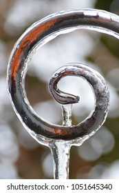 Glaciation After The Spring Thaw. Decorative Metal Support For Climbing Plants Is Covered With Ice. Icicle Hanging From The Decorative Support.