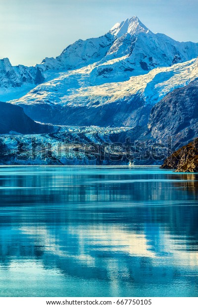 Glacier Bay Alaska cruise vacation travel.\
Global warming and climate change concept with melting ice.\
Cruising boat towards landscape of Johns Hopkins Glacier and Mount\
Fairweather Range\
mountains.