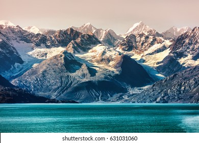 Glacier Bay National Park, Alaska, USA. Alaska cruise travel view of snow capped mountains at sunset. Amazing glacial landscape view from cruiseship vacation showing snowy mountain peaks.