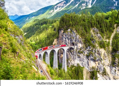 Glacier express on Landwasser Viaduct, Switzerland. It is landmark of Swiss Alps. Red Bernina train runs on railroad bridge in mountains. Aerial scenic view of railway in summer. Nice Alpine landscape
