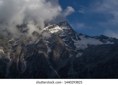 Glaciers and mountain peaks of mountain range under clouds