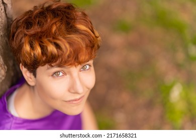 Glad Androgynous Woman Relaxing Near A Tree