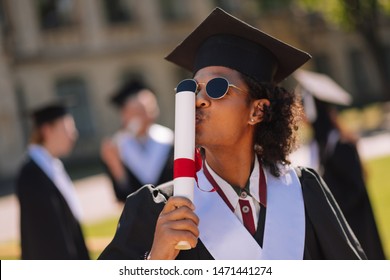 Glad to be a master. Happy graduant wearing sunglasses and a masters cap kissing his newly received diploma in the university yard. - Powered by Shutterstock