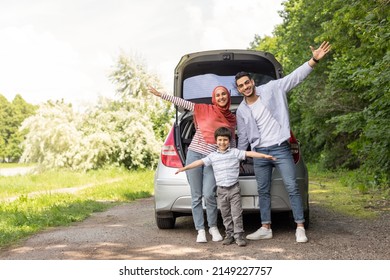 Glad Cheerful Emotional Arab Male, Female In Hijab And Little Boy Waving Their Hands Near Car Trunk, Enjoy Journey Together Outdoor In Summer. Family Trip, Vacation And Travel At Auto, Free Space