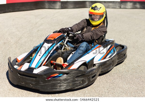 Glad cheerful positive woman\
driving sport car for karting  in a circuit lap outdoor in sport\
club