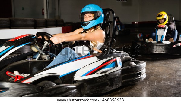 Glad cheerful  smiling woman driving\
sport car for karting  in a circuit lap in sport\
club