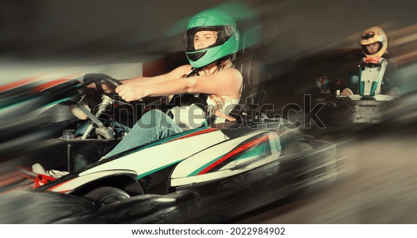 Glad cheerful smiling woman driving\
sport car for karting in a circuit lap in sport\
club