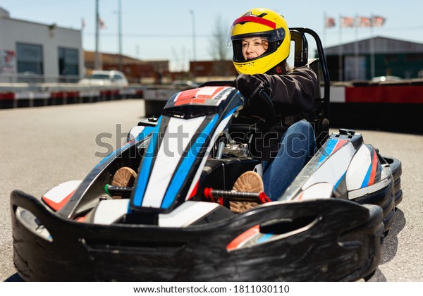 Glad cheerful woman driving sport\
car for karting in a circuit lap outdoor in sport\
club