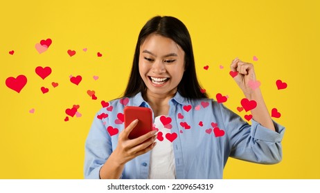 Glad Excited Young Chinese Lady Looking At Smartphone And Making Victory Gesture With Hand, Posing On Yellow Background, Studio. Happy Asian Woman Got Message From Lover, Collage