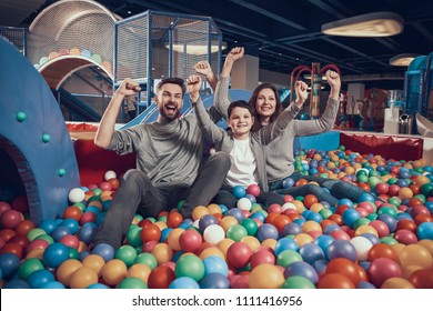 Glad Family Sitting In Pool With Balls. Family Rest, Leisure. Spending Holiday Together. Entertainment Center, Mall, Amusement Park.