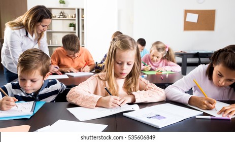Glad female professor and elementary age children at classroom