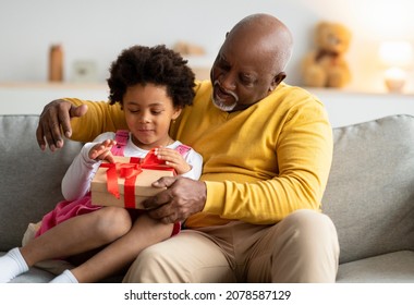 Glad Happy Cute African American Preschool Kid And Old Man Open Birthday Present In Living Room Interior, Free Space. Holiday, New Year And Event Celebration, Love, Relationships And Family, Indoor