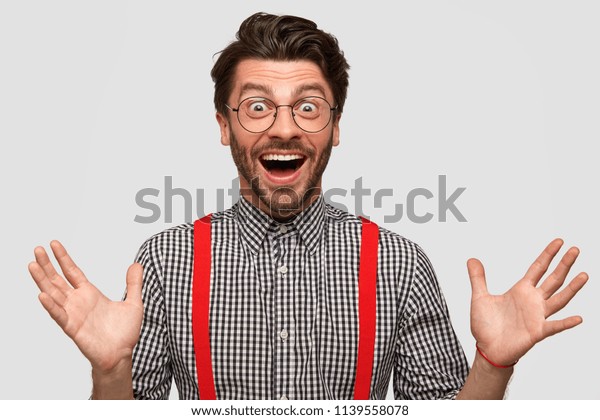 Glad hipster going to embrace old friend, rejoices meeting, has overjoyed facial expression, dressed elegantly. Young attractive cheerful man gives hug at camera, isolated over white background