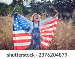 Glad kid singing with american flag in hands while closing eyes on grassy ground
